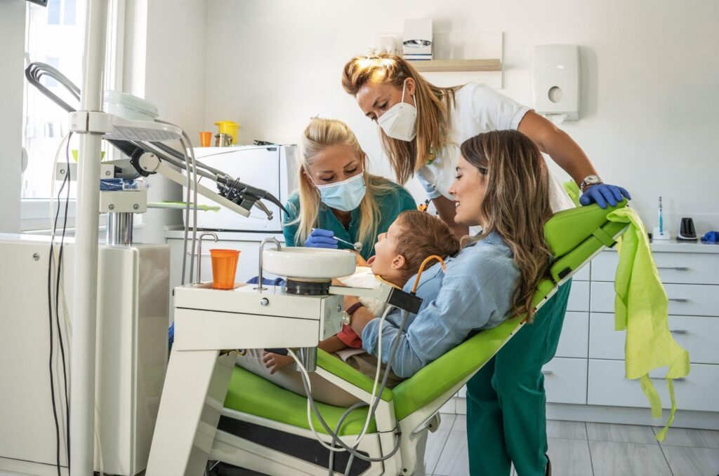 Mother supporting child during a family dental checkup in Sarasota, with caring dentists providing gentle family dental care.