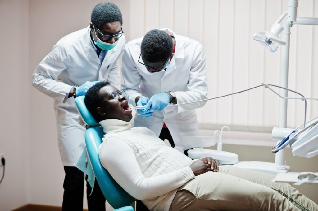 Two dentists examining a patient during a dental checkup, highlighting modern restorative dentistry and patient-focused smile repair care.