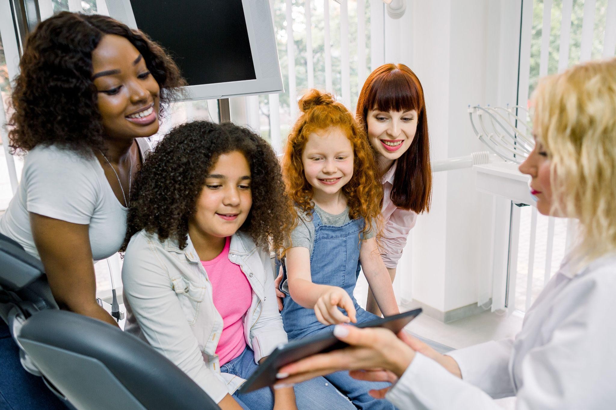 Group of children with their mothers visiting a Sarasota family dental office, learning about care in a welcoming environment.