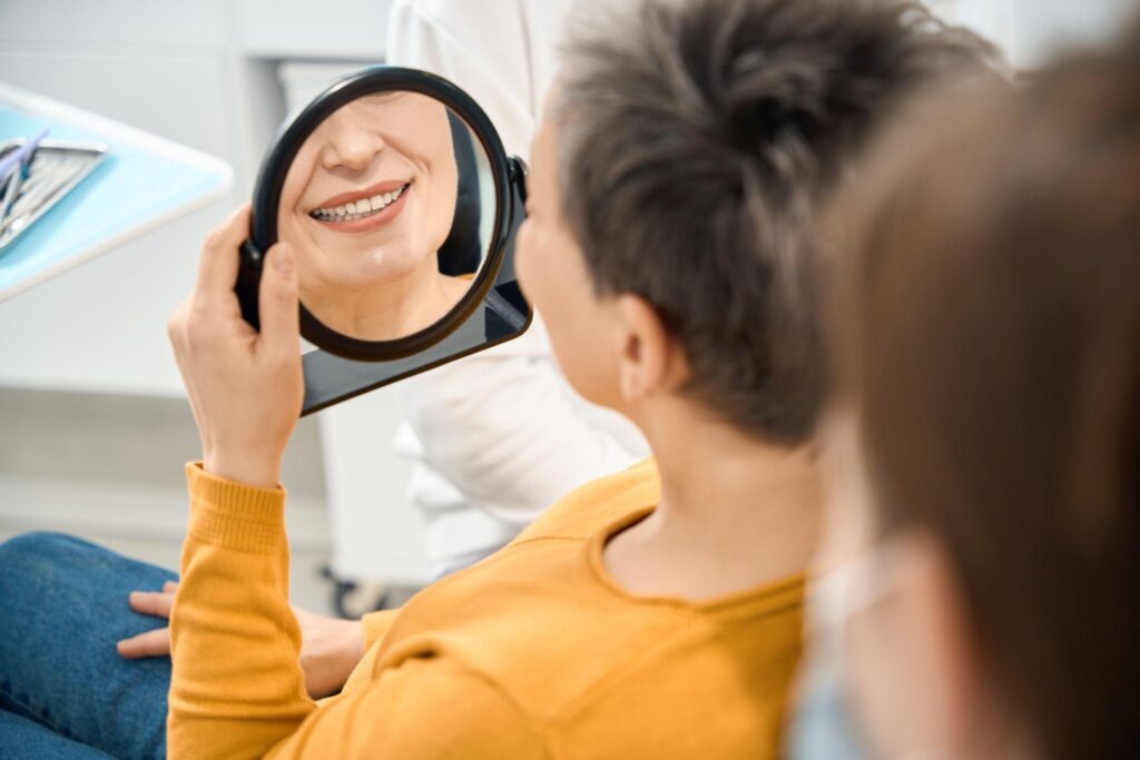 Patient checking her bright new smile after cosmetic dentistry treatment with the best dentist in Bradenton, FL; dentist Bradenton Florida offering veneers and whitening.