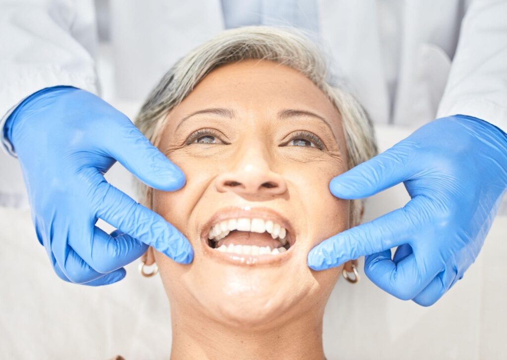 Senior woman getting a dental exam to discuss dental bridges vs implants at a Bradenton restorative dentistry appointment.