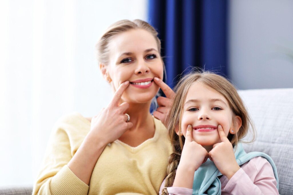Mother and daughter smiling together at home, showing healthy teeth after aesthetic family dentistry in Bradenton.