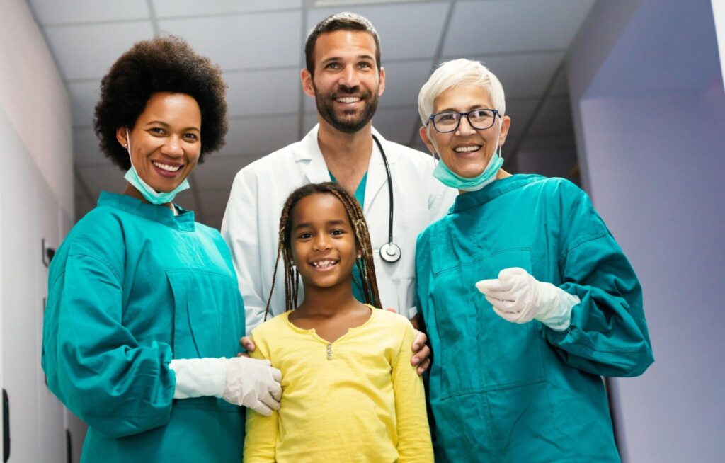 A team of family dentists and dental assistants standing with a smiling child patient, highlighting trusted, experienced dental care for families in Sarasota, FL. 